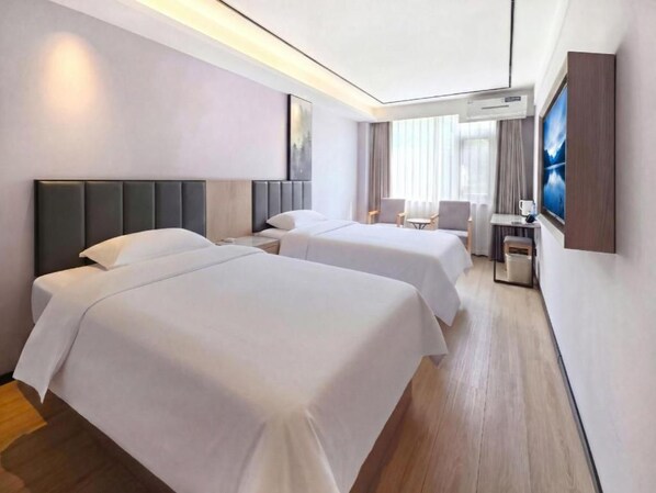 A hotel room with two beds, a desk, a chair, and a television.