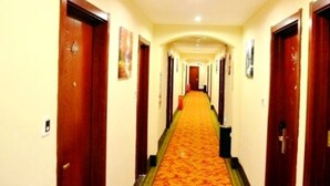 A hotel hallway with wooden doors, a carpeted floor, and a light-colored wall. - Greentree Inn Langfang Guangyang District Guangyang Avenue North Yongxing Road Express Hotel (Langfang)
