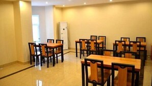 A dining area with multiple wooden tables and chairs, a white door, and recessed ceiling lights. - Greentree Inn Langfang Guangyang District Guangyang Avenue North Yongxing Road Express Hotel (Langfang)