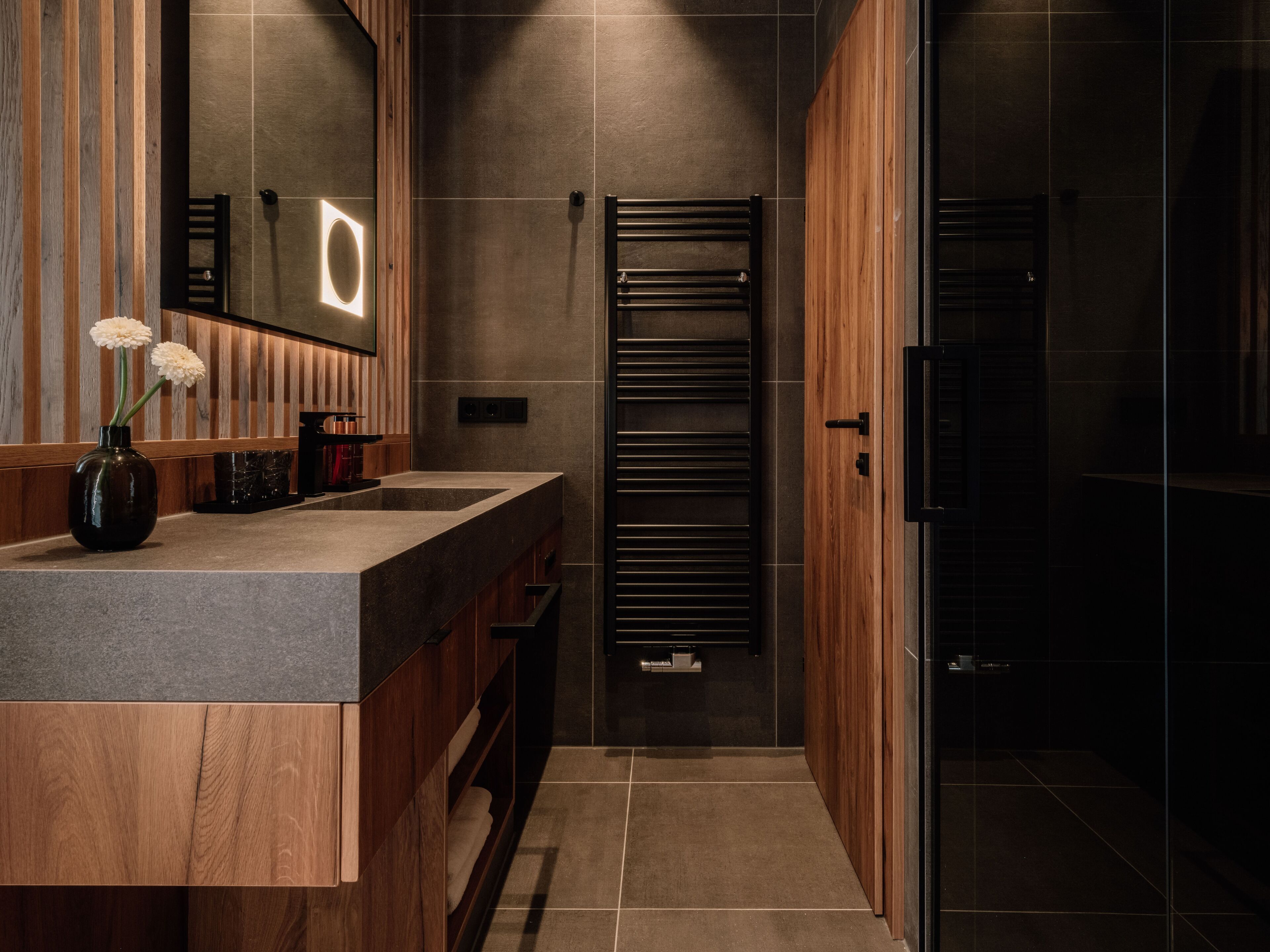 Une salle de bain moderne avec un meuble-lavabo en bois, un porte-serviettes et une cabine de douche en verre.