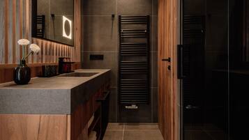 Une salle de bain moderne avec un meuble-lavabo en bois, un porte-serviettes et une cabine de douche en verre.