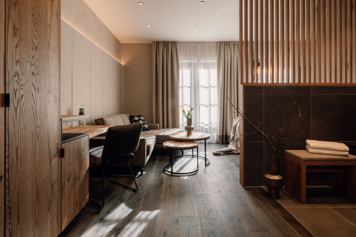 Une pièce moderne et bien éclairée, dotée d’un plancher en bois, d’un canapé, d’un bureau et d’une petite table.