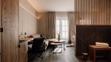 Una habitación moderna y bien iluminada con piso de madera, un sofá, un escritorio y una pequeña mesa.
