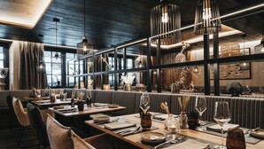 Un restaurant avec des tables en bois, des chaises noires et des lampes suspendues.