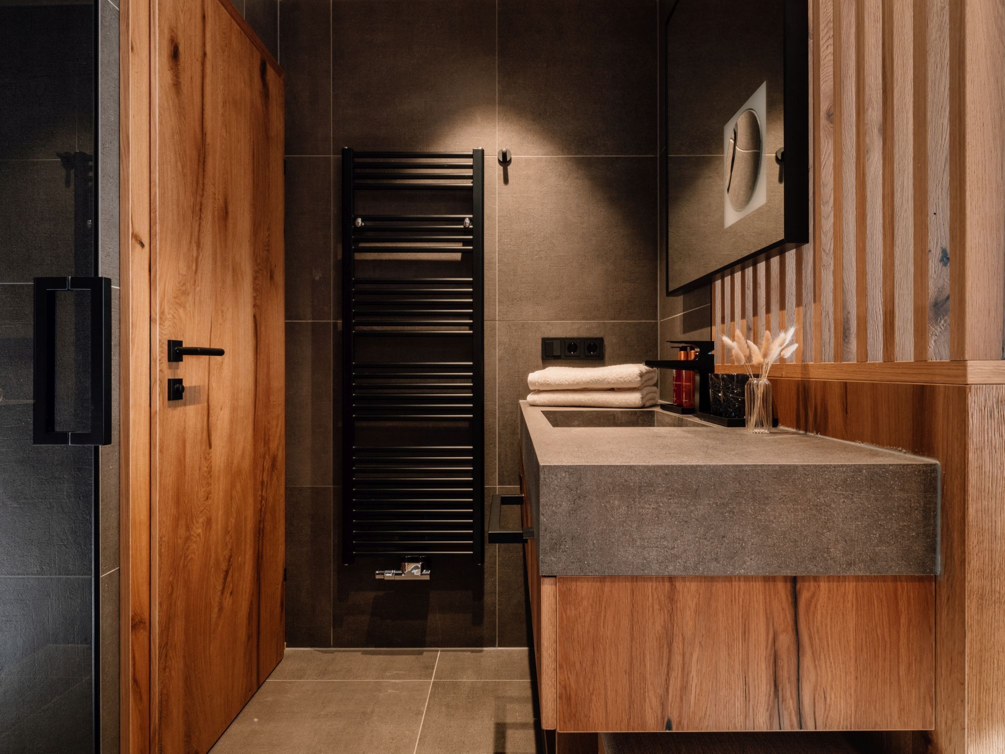 A modern bathroom with a wooden vanity, a towel rack, and a mirror.