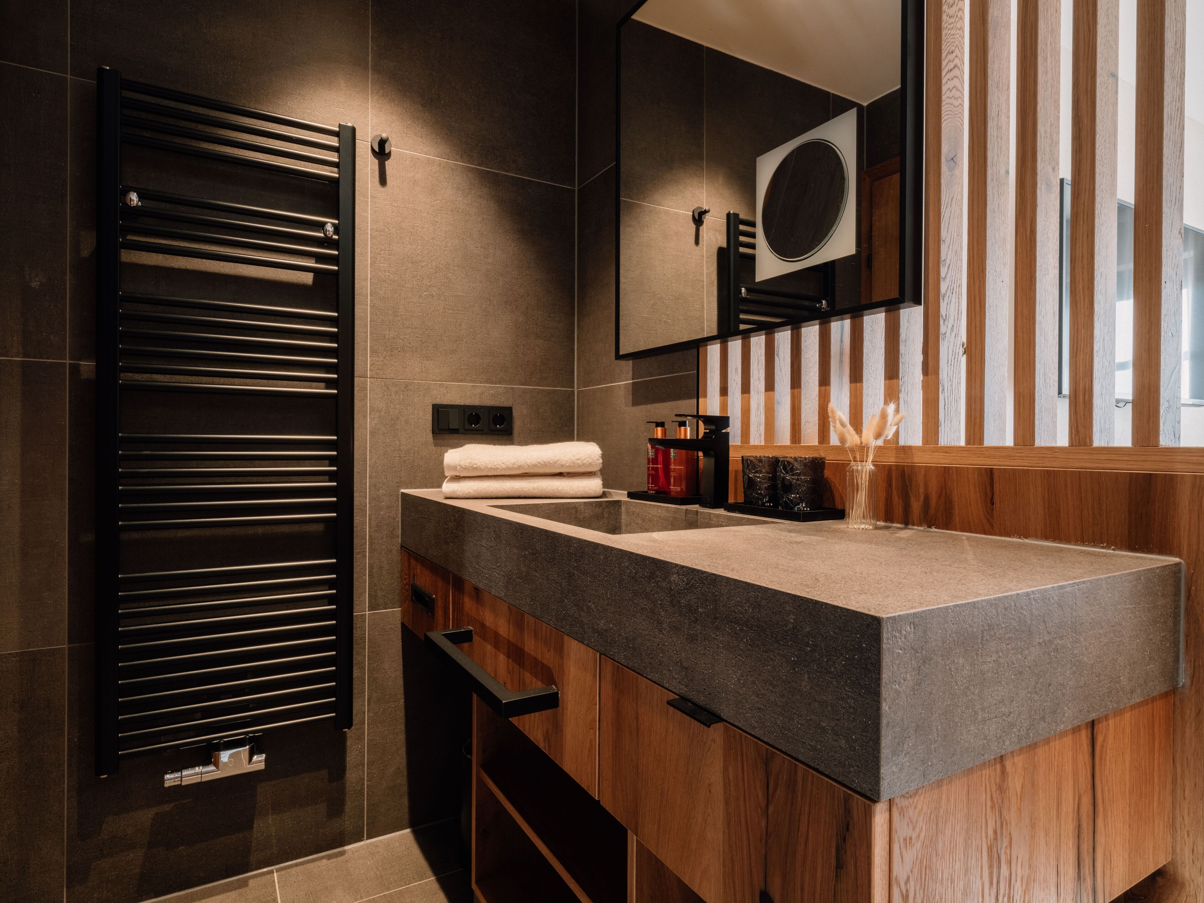 A modern bathroom with a large mirror, a towel rack, and a wooden vanity.
