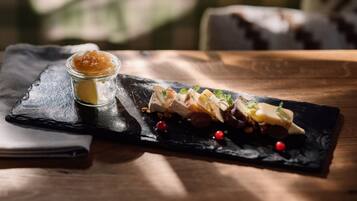 A dessert platter on a slate board with a small jar of jam and scattered berries.