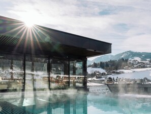 Un edificio moderno con grandes ventanales de vidrio que dan a un paisaje nevado y una piscina reflectante.