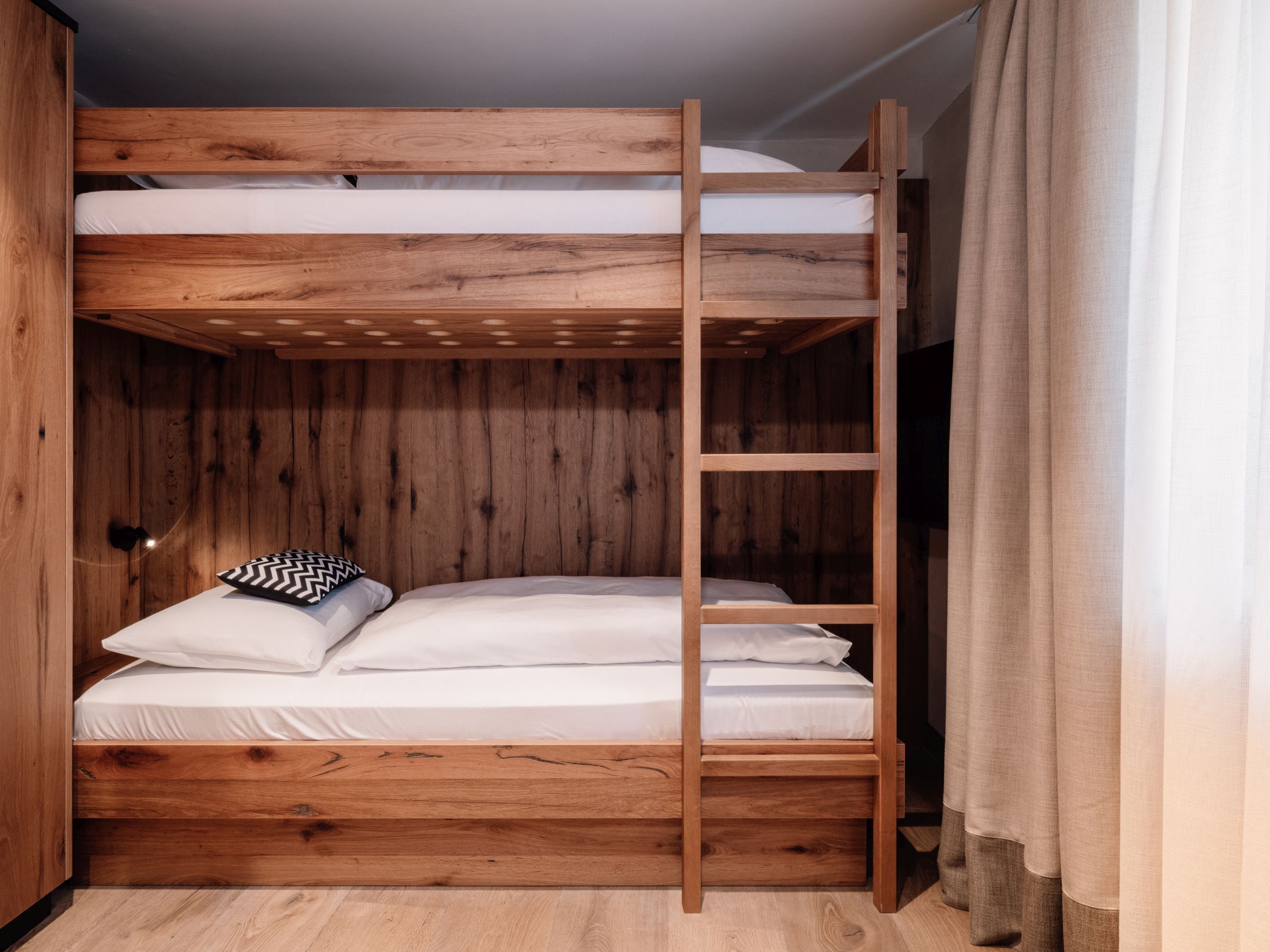 A bunk bed with a wooden frame and white bedding.