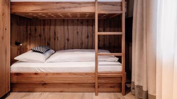 A bunk bed with a wooden frame and white bedding.