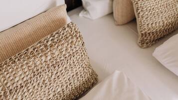 A bed with white linens and two beige, textured pillows.