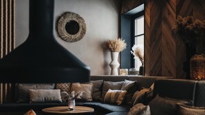 A cozy living room with a dark sofa, patterned cushions, a round coffee table, and a fireplace. - JOHANN Schladming Hotel GmbH (Schladming)
