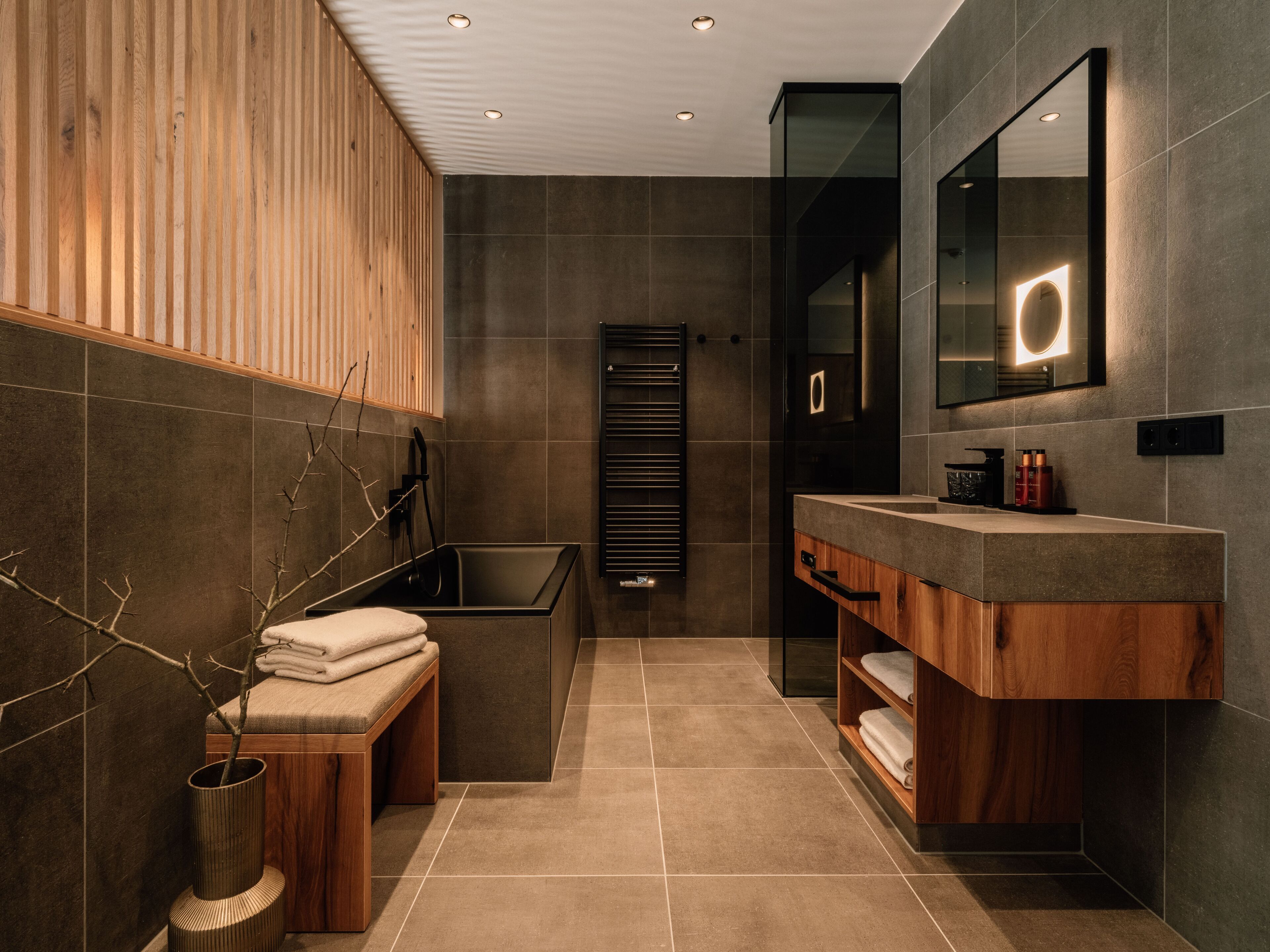 Une salle de bain moderne avec un meuble-lavabo en bois, un grand miroir et une baignoire intégrée.
