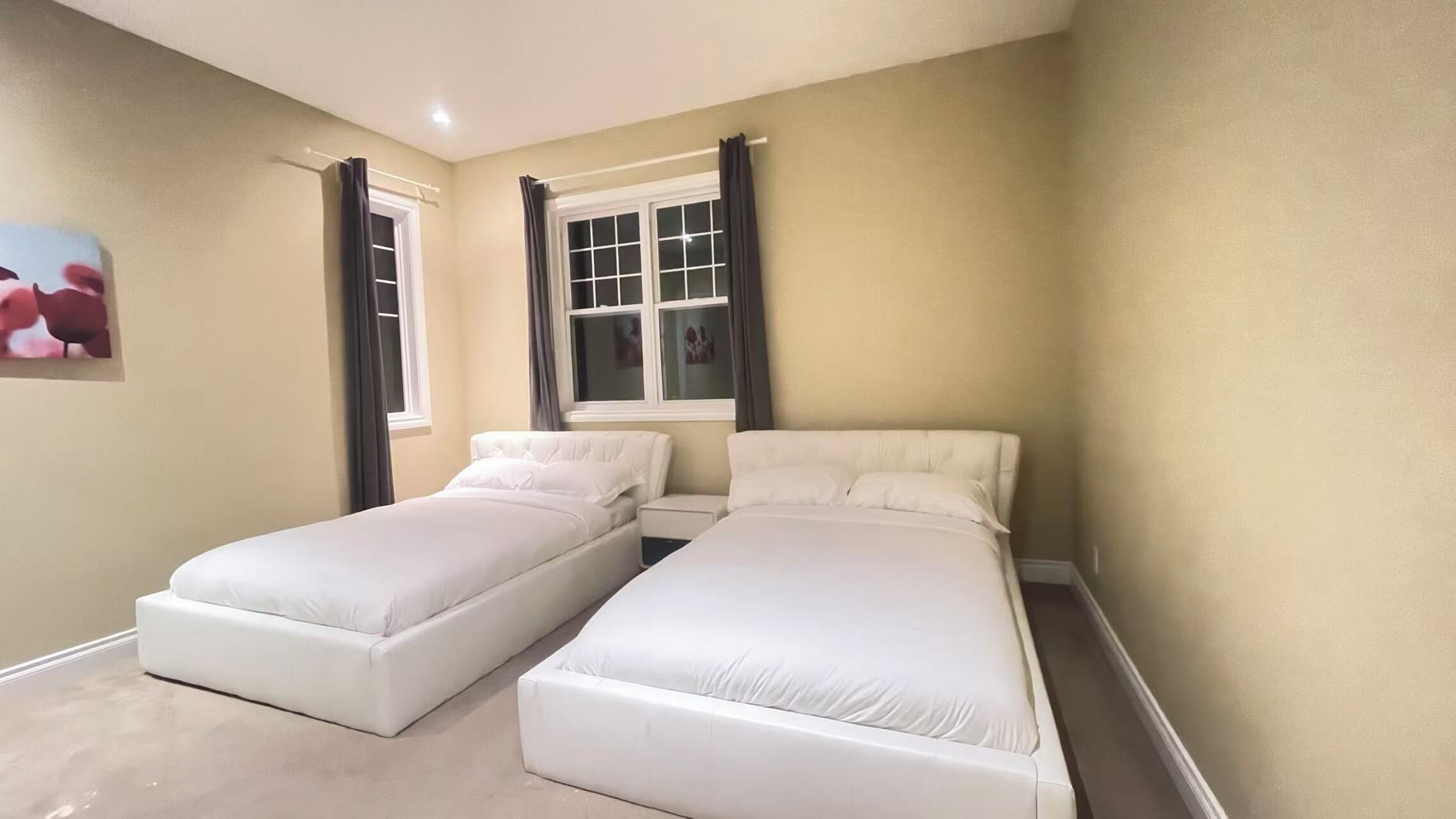 Une chambre avec deux lits, une fenêtre avec des rideaux et un tableau au mur.