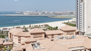 A coastal hotel with a beach view, a pier, and a high-rise building in the background. - Maison Privee - Premium Studio Apt in the Heart of JBR Beach, Dubai (Dubai)