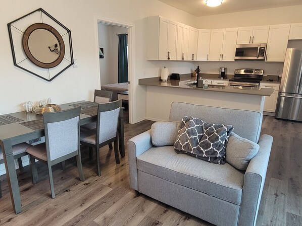 A modern kitchen with white cabinets, a stainless steel refrigerator, and a built-in oven. - #201 New Cozy Monroe Condo near Evergreen State Fair! (Monroe)