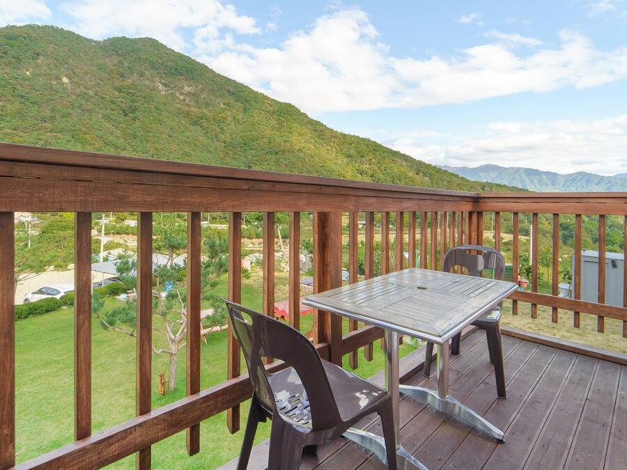 Una terraza de madera con mesa y sillas, con vista a un paisaje montañoso.