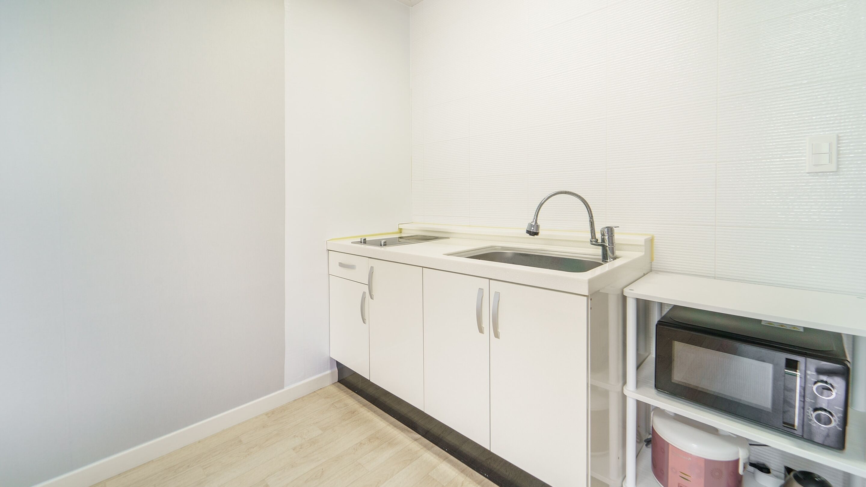 A small kitchenette with a double sink, a microwave, and a small refrigerator.