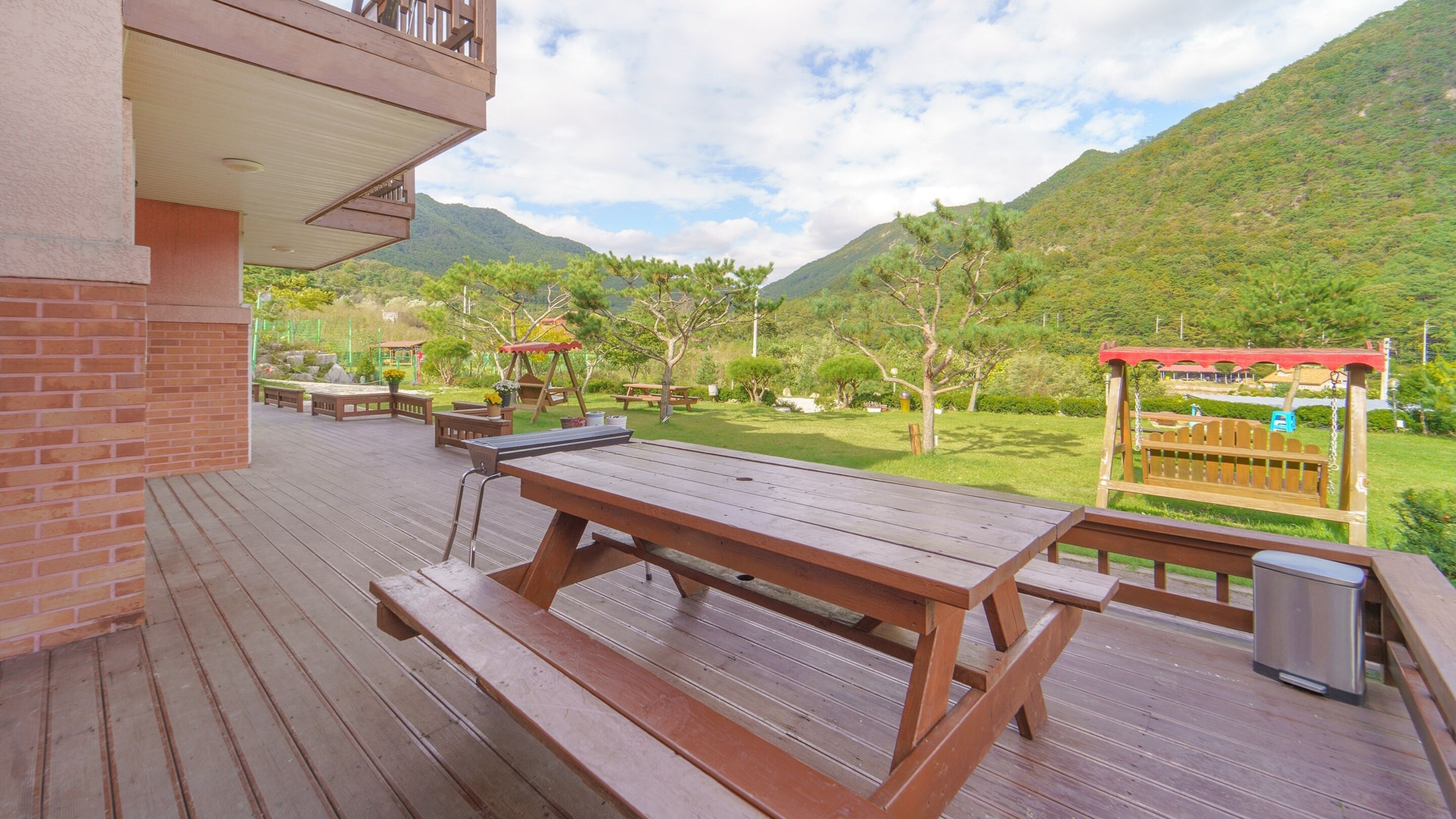 Eine Holzterrasse mit Picknicktischen und Blick auf eine gebirgige Landschaft.