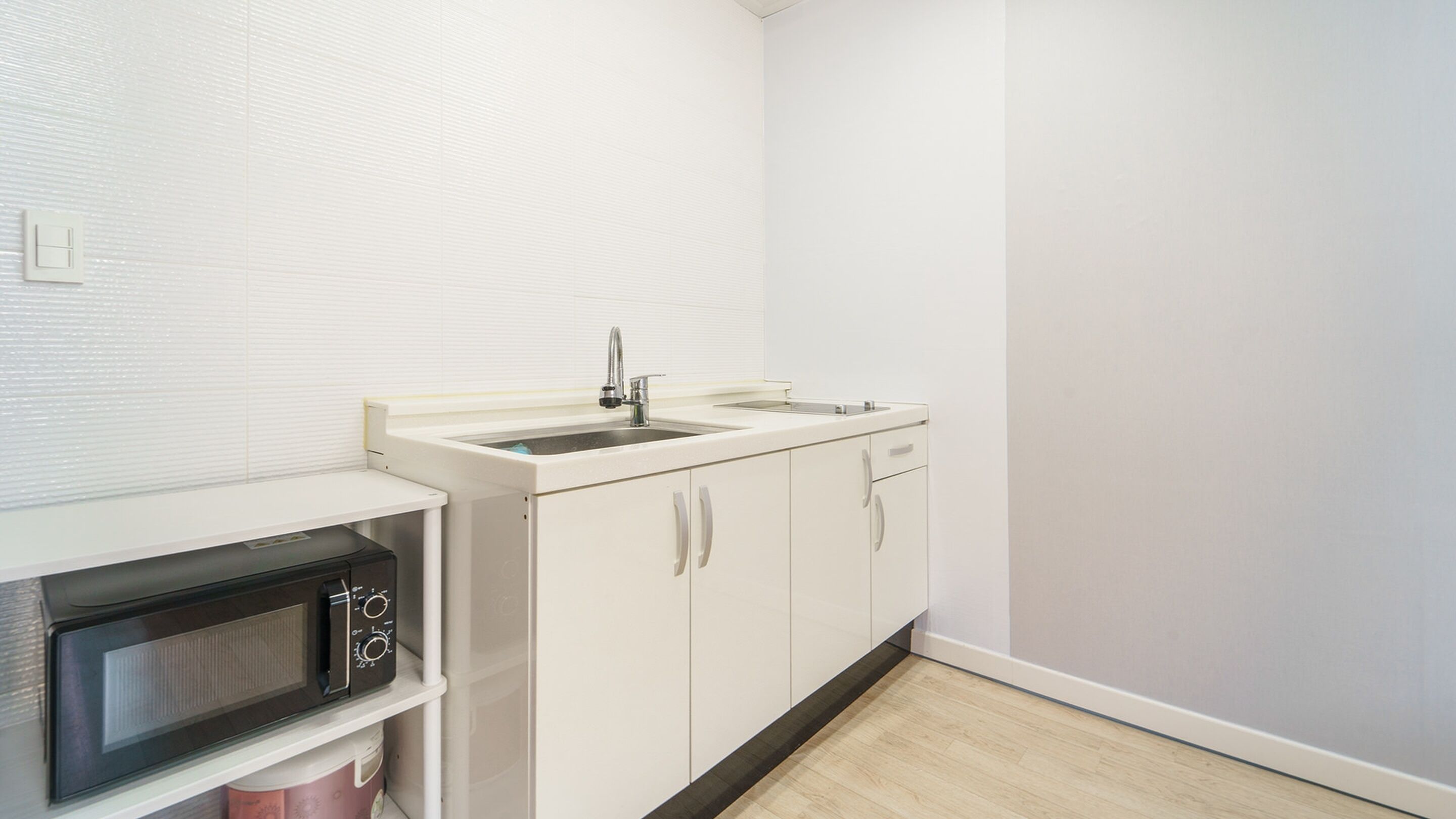 A compact kitchen with a microwave, sink, and cabinets.