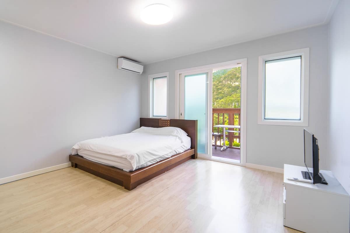 A bedroom with a bed, a window, and an air conditioning unit.