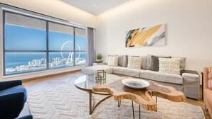 A modern living room with a large window, a round coffee table, a sofa, and a view of a Ferris wheel. - Maison Privee - Sun Sand & Dubai Luxury at JBR Beach (Dubai)