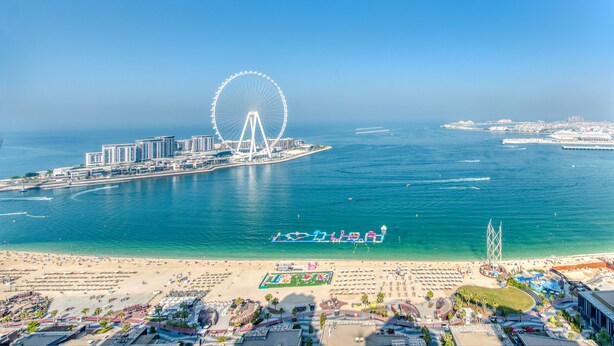 A coastal cityscape with a prominent Ferris wheel, beachfront hotels, and a marina. - Maison Privee - Sun Sand & Dubai Luxury at JBR Beach (Dubai)