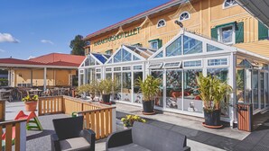A hotel with outdoor seating, potted plants, and a glass-enclosed veranda. - Björkbackens Vandrarhem i Vimmerby - Hostel (Vimmerby)