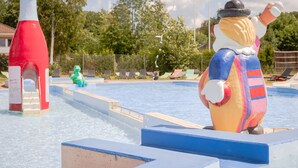 A water park with a large inflatable figure, a red water slide, and lounge chairs. - Björkbackens Vandrarhem i Vimmerby - Hostel (Vimmerby)