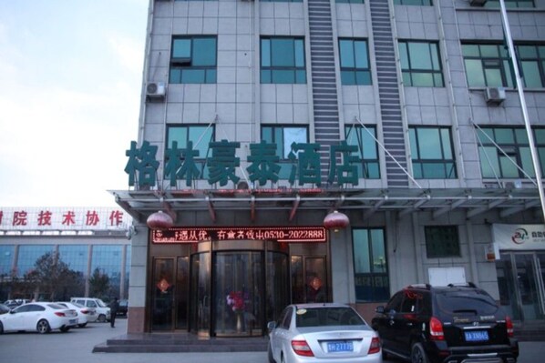 A hotel entrance with a signboard, a staircase, and parked cars. - Greentree Inn Heze Juye West No.1 Middle School Hotel (Heze)