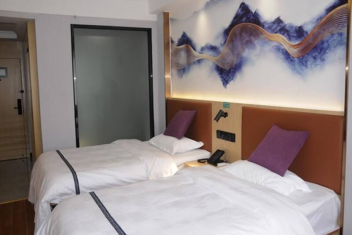 Una habitación de hotel con dos camas, un teléfono en la pared y una puerta.