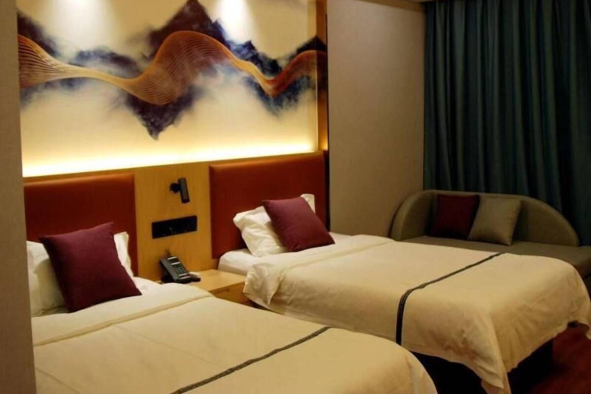 Habitación de hotel con dos camas, un teléfono en la pared y un cuadro grande.
