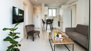 Un salon moderne avec un canapé, une table basse sur laquelle sont posés des magazines, un téléviseur et une plante en pot.