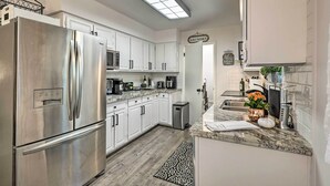 A modern kitchen with white cabinets, stainless steel appliances, and a granite countertop. - Renovated Cottage w/ Fire Pit in Munds Park! (Munds Park)