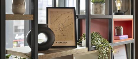 Una estantería con un mapa enmarcado de Romford, libros y objetos decorativos.