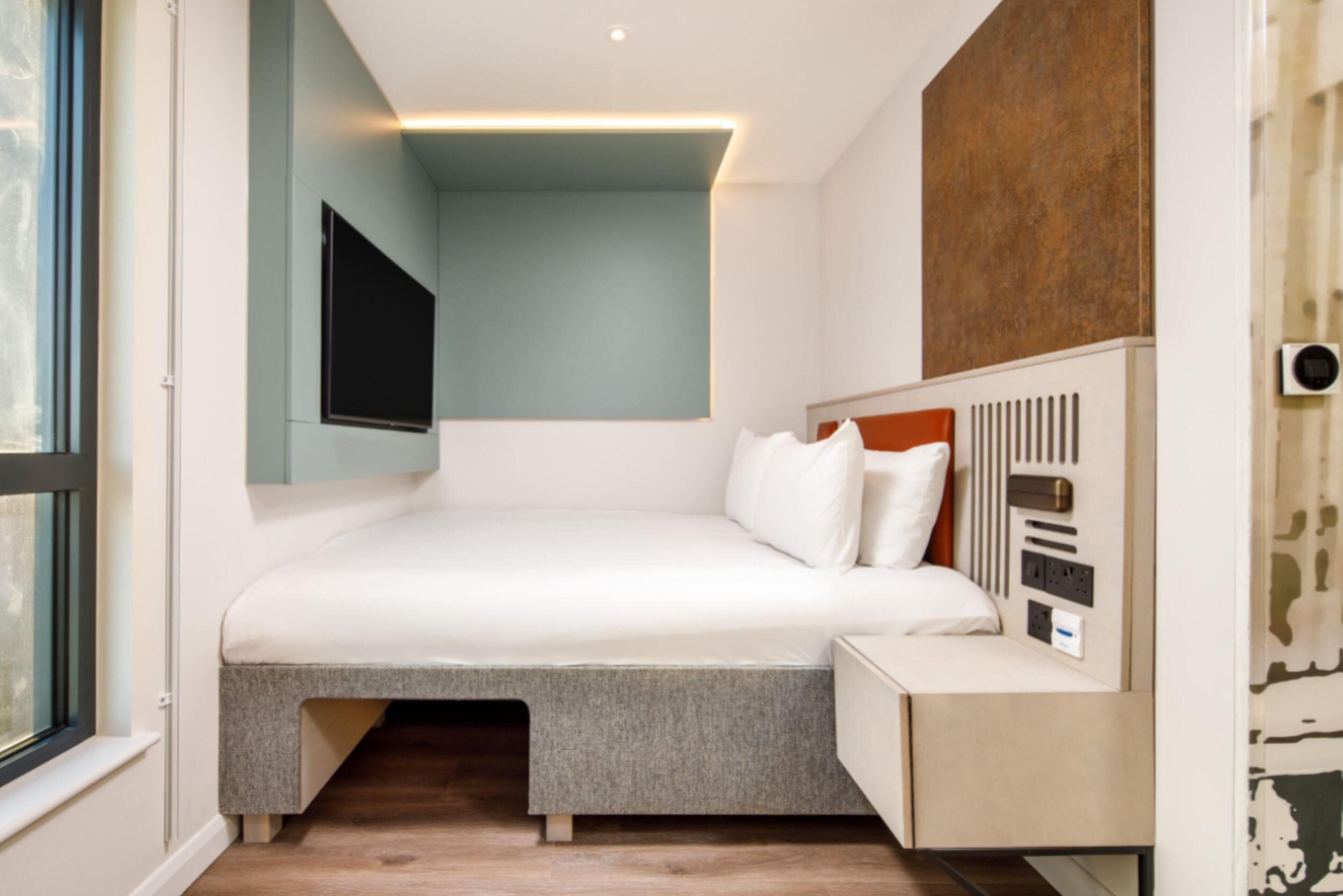 A modern bedroom with a bed, bedside table, and a built-in storage unit.