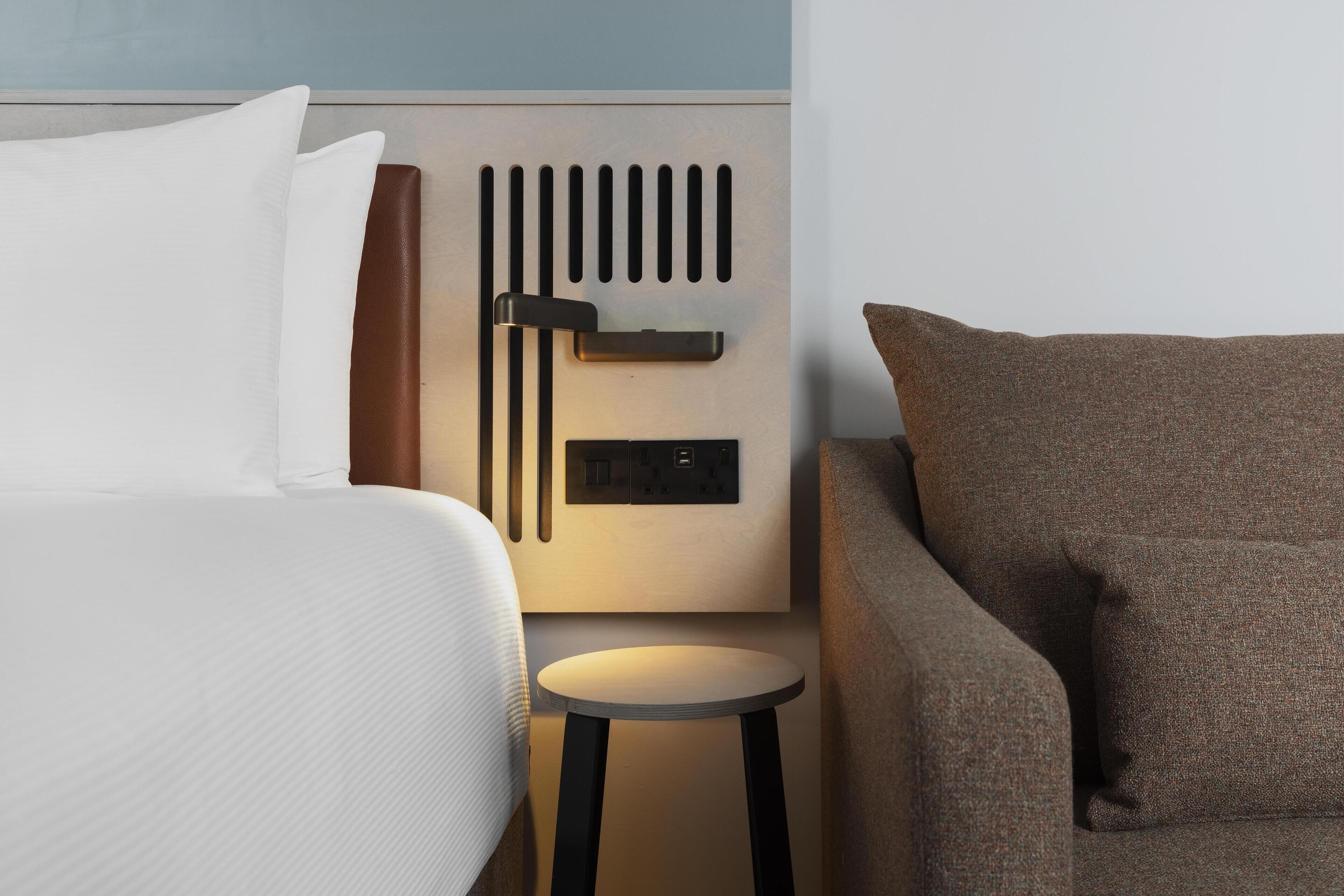 Ein modernes Hotelzimmer mit einem Bett, einem kleinen runden Tisch und einer Couch.