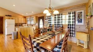 A spacious kitchen with wooden cabinets, a central island, and a dining area with a checkered table runner. - Bring a Pet! Mtn-View Bostic Retreat w/ Deck (Bostic)