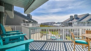 A wooden deck with outdoor seating, a view of a swimming pool, and adjacent buildings. - Pool w/ Spa! Beachfront Condo in Port Aransas (Port Aransas)