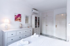 Ein Schlafzimmer mit einem Bett, einem Schminktisch, einem Kleiderschrank, einer Kommode und einem Bild an der Wand.