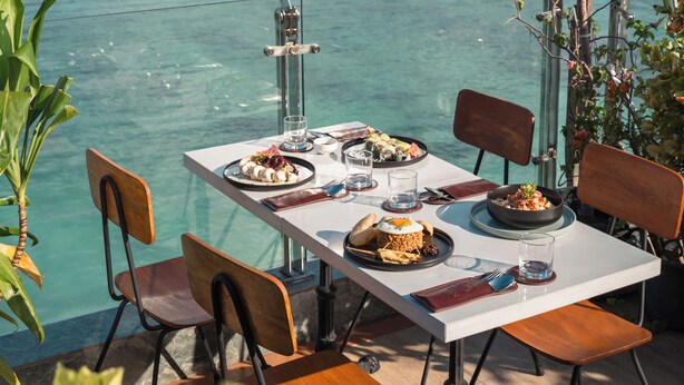 A table set with plates of food, chairs, and a view of the ocean. - Amber Beach (Hulhumalé)