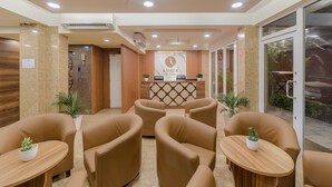 A reception area with a reception desk, seating, and a ceiling fan. - Amber Beach (Hulhumalé)