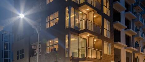 Un hotel de varios pisos con balcones, entrada a nivel de calle y fachada bien iluminada.