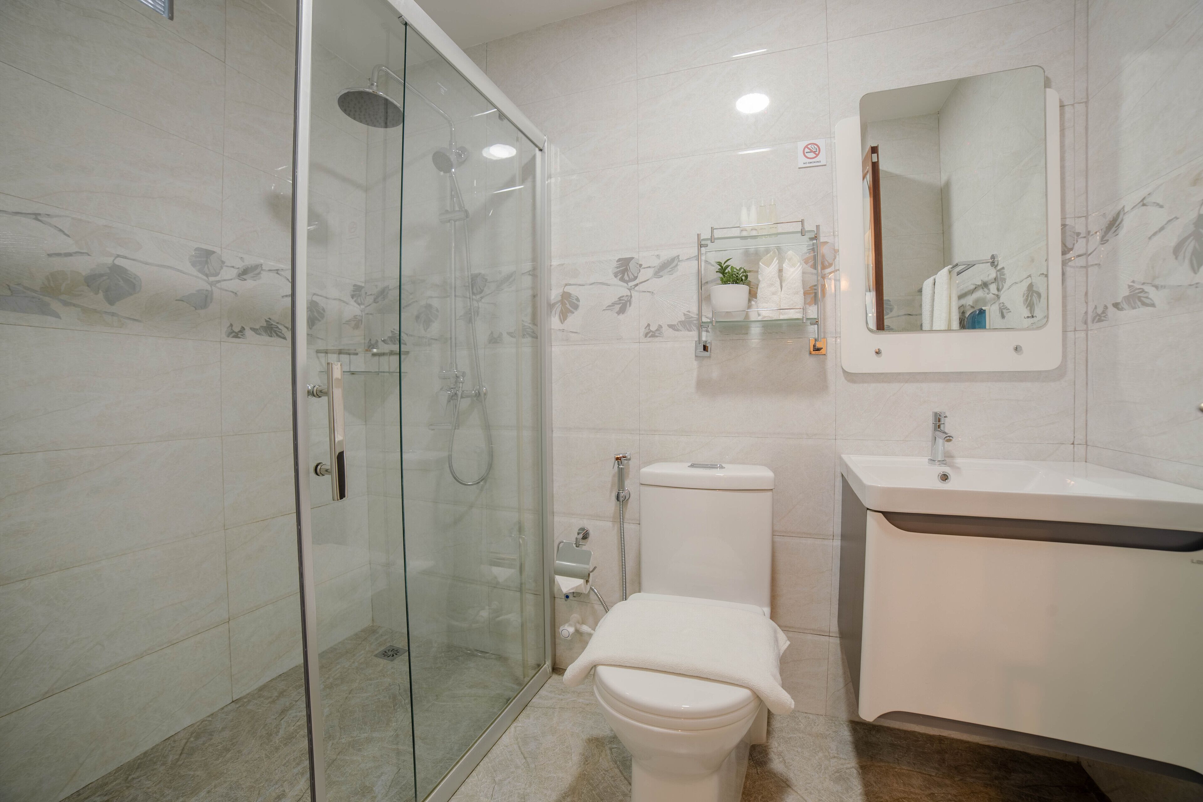 Ein modernes Badezimmer mit einer Duschkabine, einer Toilette und einem Waschbecken mit Spiegel.