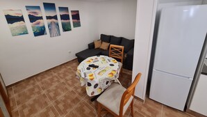 A compact living space with a dining area, a sofa, and a refrigerator. - Apartment in Tenerife South (Cabo Blanco - Arona)