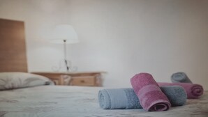 A bed with rolled towels in blue and pink, a wooden nightstand, and a white wall. - Apartment in Tenerife South (Cabo Blanco - Arona)