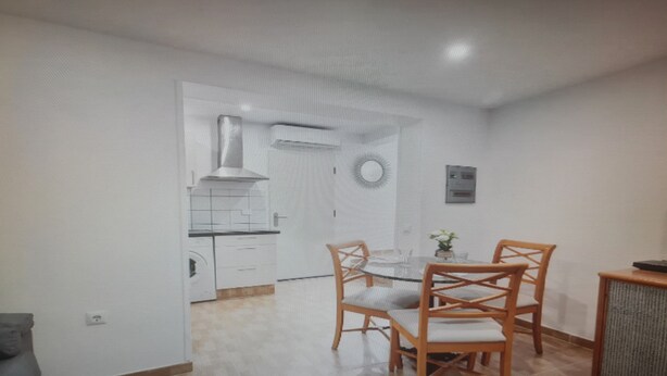 A room with a dining table and chairs, a small plant on the table, and a wall-mounted light fixture. - Apartment in Tenerife South (Cabo Blanco - Arona)