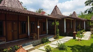 A row of traditional wooden houses with tiled roofs and a paved pathway leading to the entrance. - Balkondes Borobudur Karanganyar (Magelang)