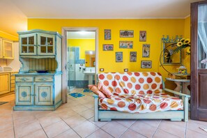 A room with a sofa, a cabinet, and a wall with pictures. - Villa Gialla Castiadas with Mountain View, Terrace & A/C (Castiadas)