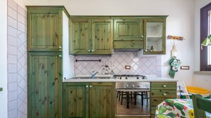 Une cuisine avec des meubles de rangement verts, une cuisinière et un évier.